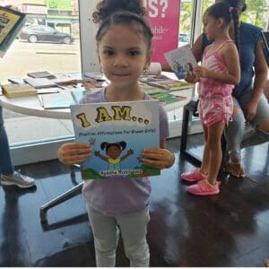 Child Smiling holding I Am Positive Affirmations for Brown Girls